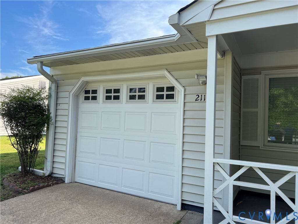 2112 Paramont Avenue, Collegue Park, Chesapeake, VA 23320 White paneled garage door with upper window inserts, light-colored siding, and a covered entry with decorative railing