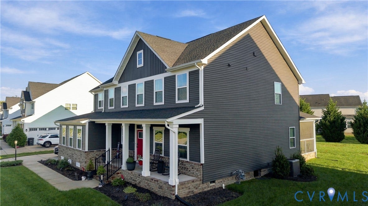 Two-story residence featuring dark gray siding, a full-width front porch with white columns, and a stone foundation