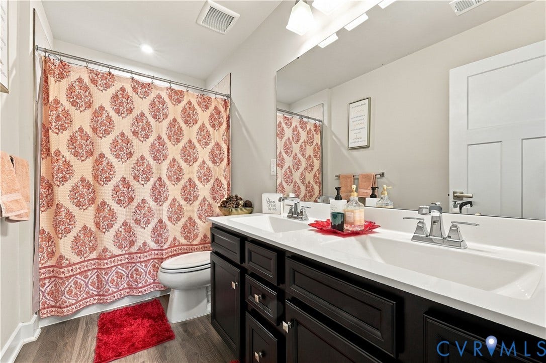 Double vanity with integrated sinks, chrome fixtures, dark wood-finish cabinetry, and wood-finish flooring