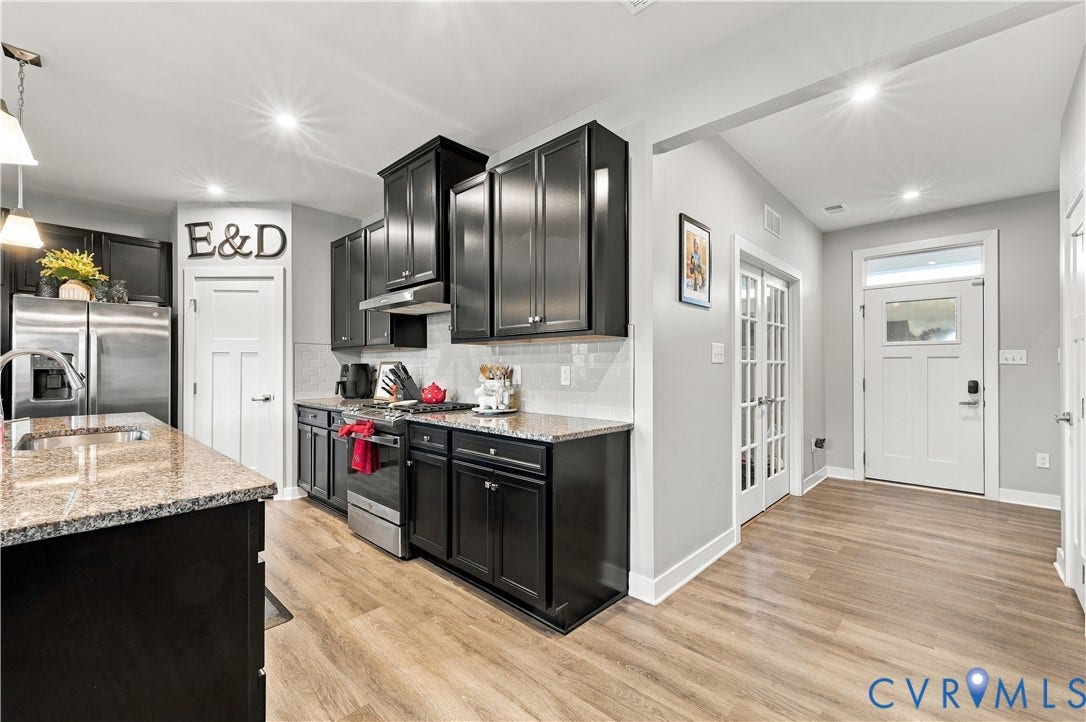 Kitchen featuring dark cabinetry, light-toned countertops, stainless steel appliances, and wood-finish flooring