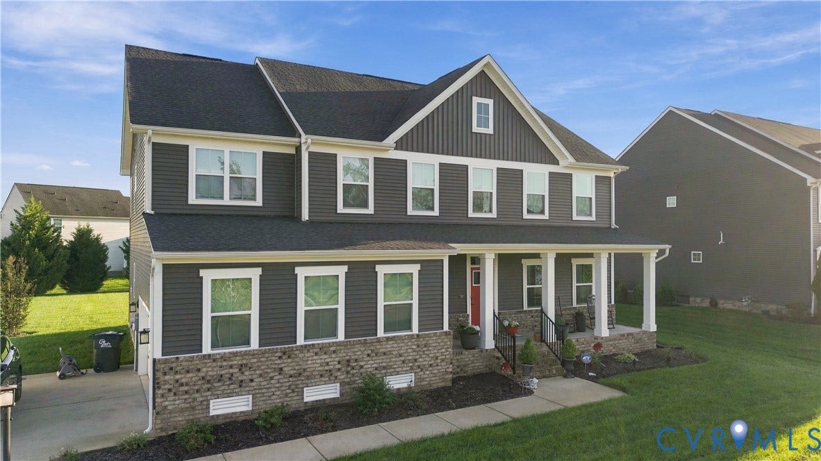 Two-story exterior with dark siding, white trim, a covered front porch, and a red front door