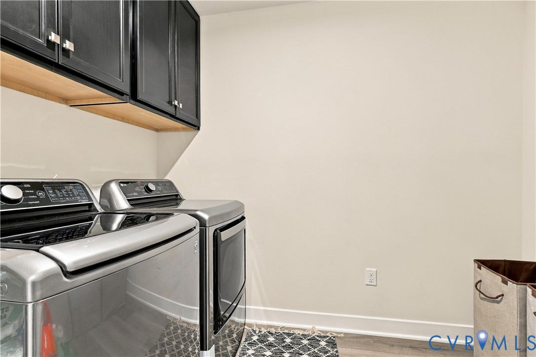 Upper black cabinetry with brushed nickel hardware, wood-finish flooring, and light-toned walls