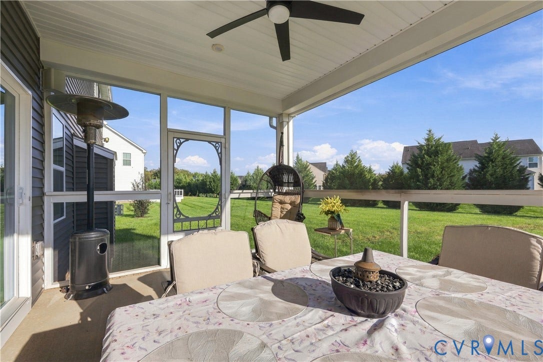 Screened-in porch with ceiling fan and access to a manicured lawn