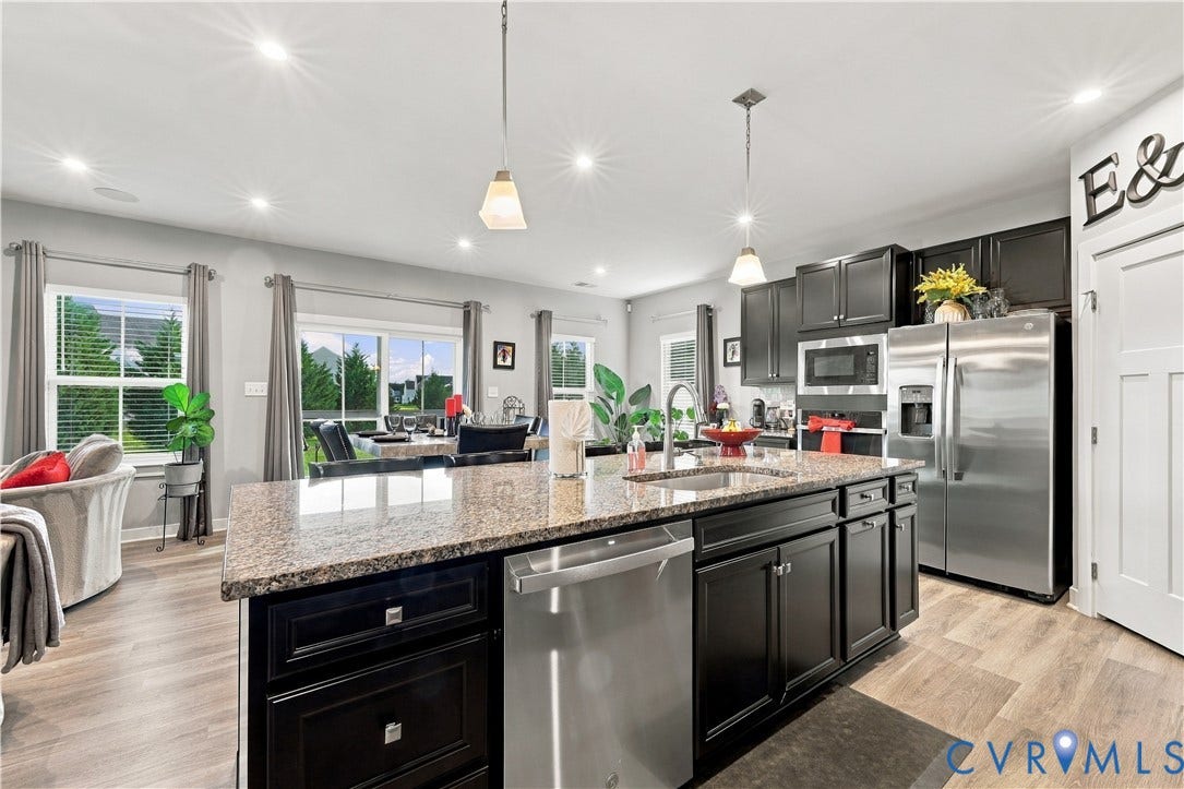 Kitchen featuring an expansive island with a stone countertop, dark cabinetry, and stainless steel appliances