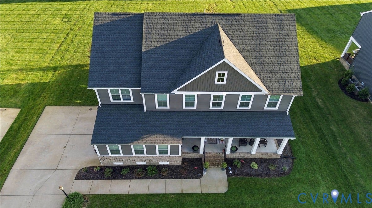 Two-story residence featuring a covered front porch, concrete driveway, and dormer window
