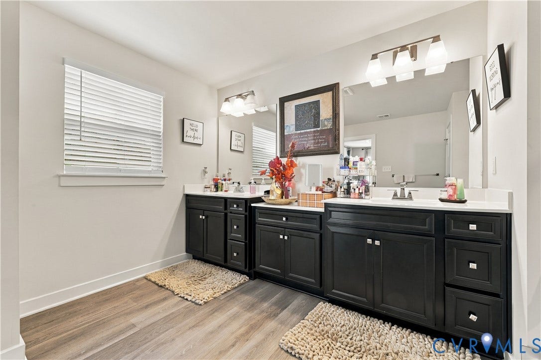 Dual vanity with dark cabinetry, white countertops, and wood-finish flooring