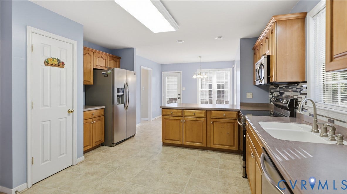 Kitchen featuring wood cabinetry, stainless steel appliances, a tiled backsplash, and an island