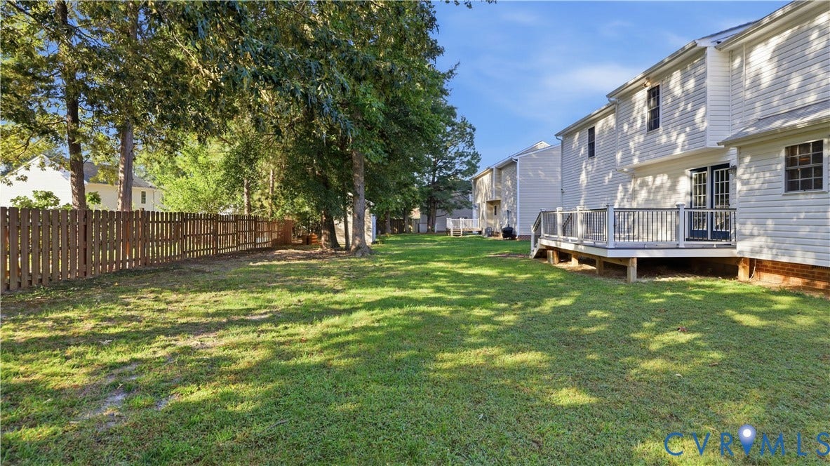 Expansive lawn with a wood privacy fence and mature trees