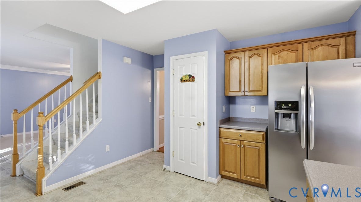 Wood-finish cabinetry paired with a stainless steel refrigerator and light-toned countertops