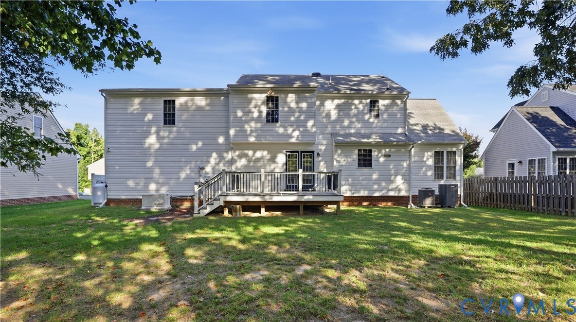 Wood deck with black railing and steps, dual French doors, white siding, and a manicured lawn