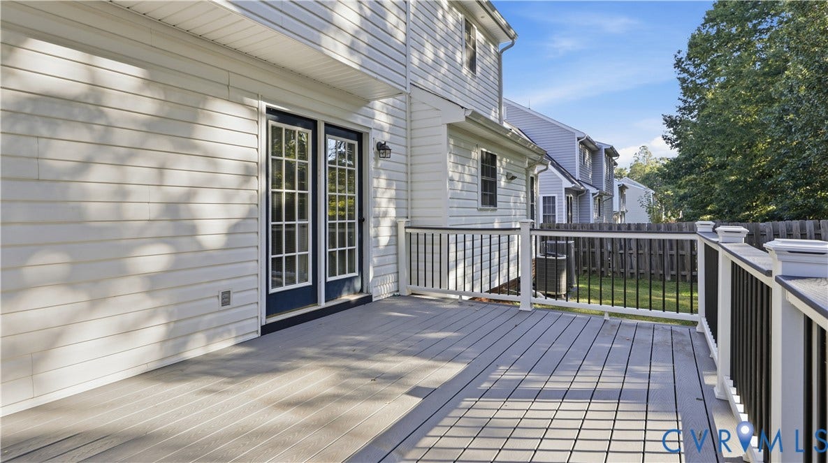 Spacious outdoor deck with composite decking and white railing, featuring black balusters