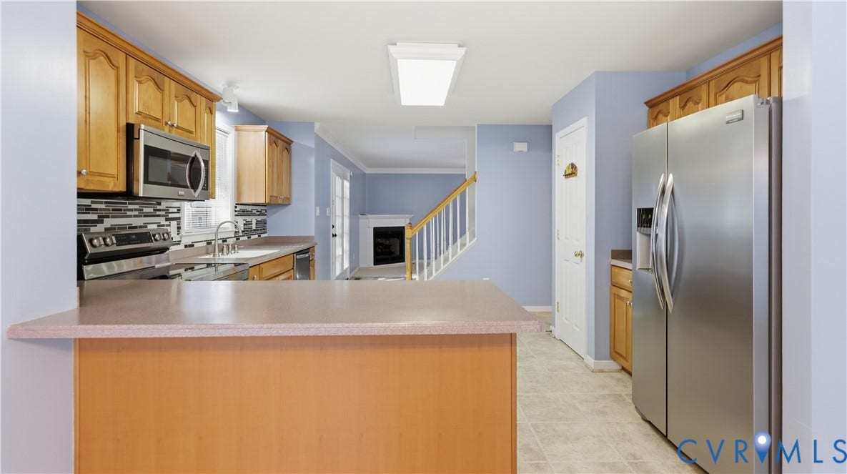 Kitchen featuring wood-finish cabinetry, stainless steel appliances, a tile backsplash, and a breakfast bar