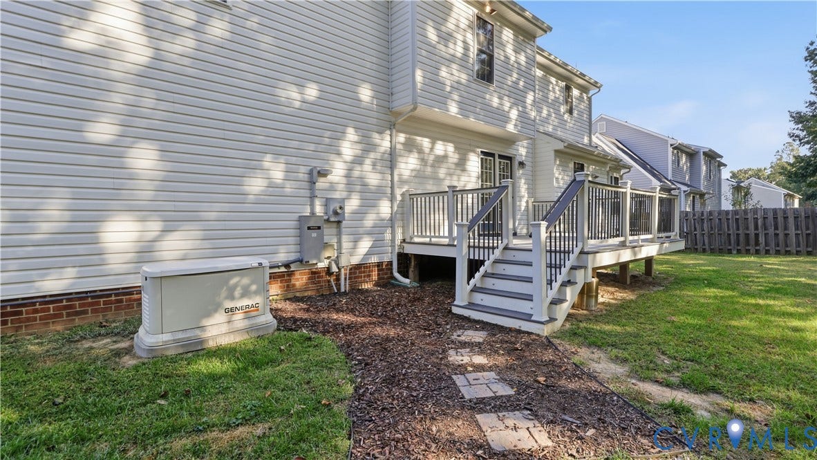 Rear exterior featuring white horizontal siding, a multi-level deck with white and grey railings, a sliding glass door, and a Generac whole-house generator