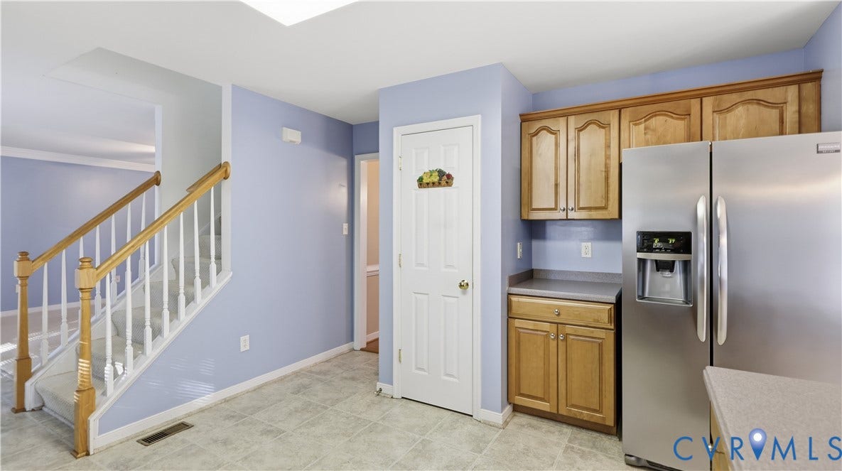 Kitchen area featuring wood cabinetry, stainless steel refrigerator, and tiled flooring