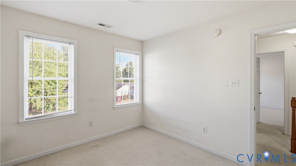 Neutral wall color with white trim, two multi-pane windows, and carpet flooring