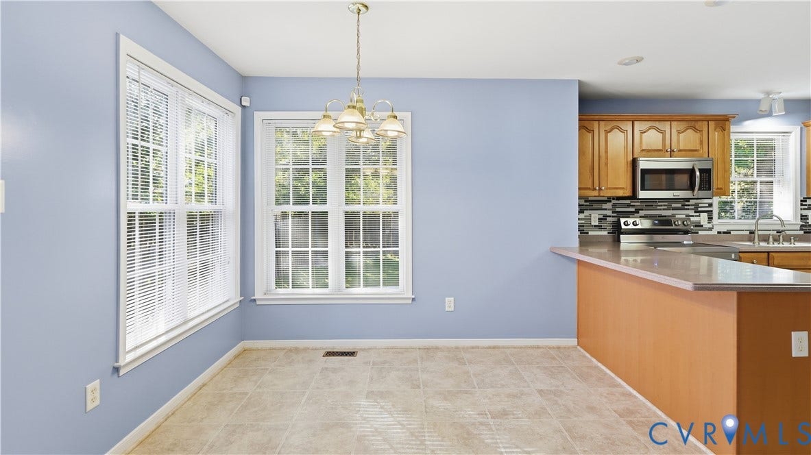 Dining area with tiled flooring, two multi-pane windows, and an overhead chandelier