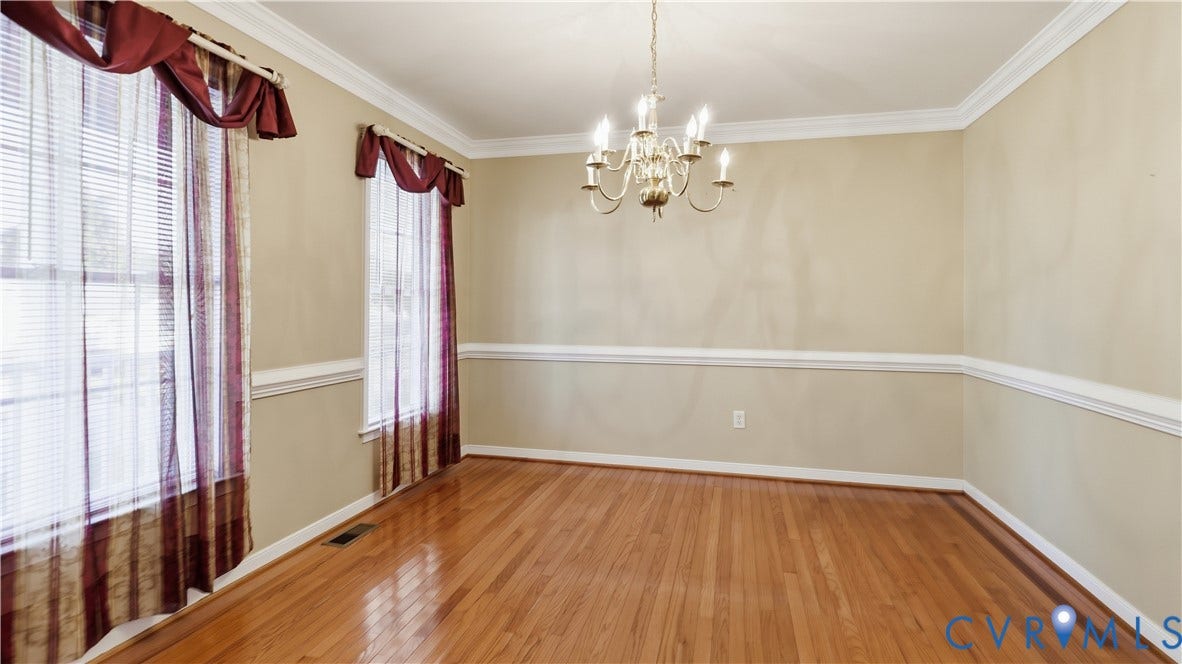 Hardwood flooring, crown molding, chair rail, and an overhead chandelier