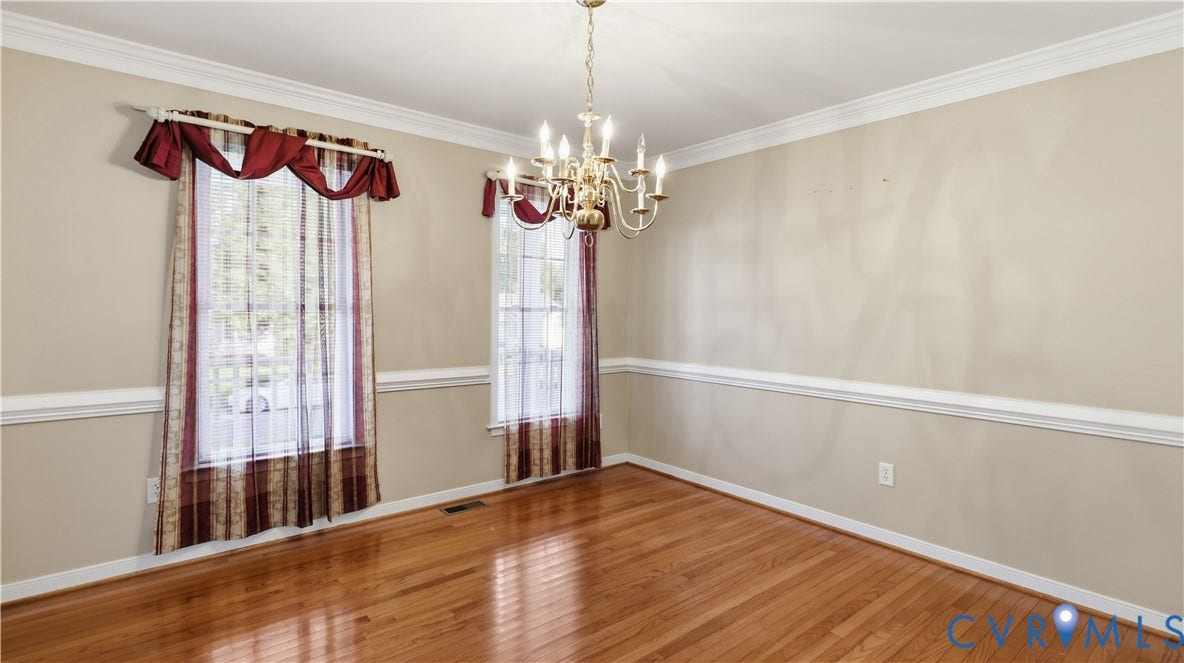 Hardwood flooring, crown molding, chair rail molding, two windows, and a brass chandelier