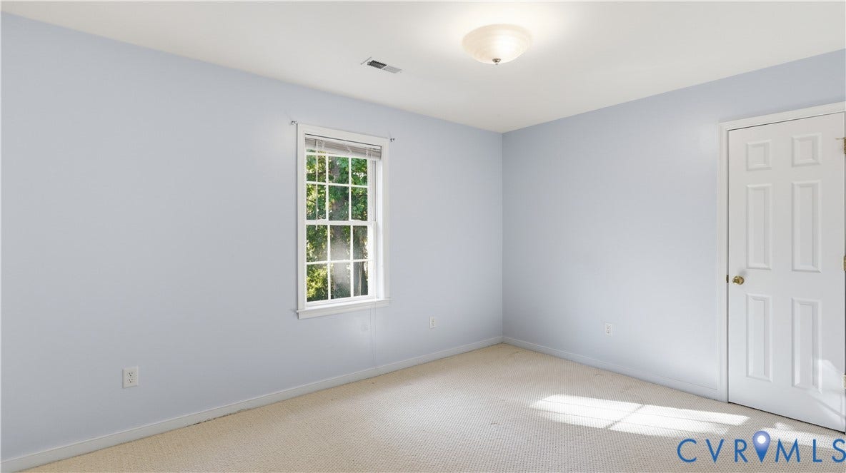 Neutral wall paint, carpet flooring, a window with muntins, a paneled door, and a flush mount light fixture