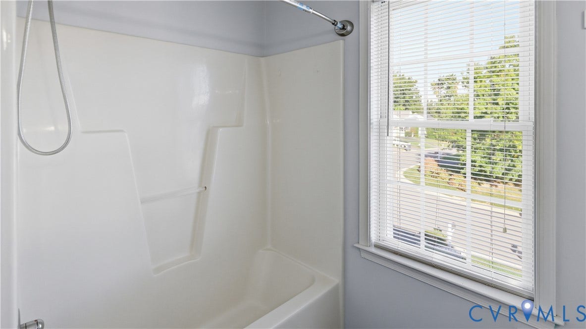 White fiberglass tub and shower combination with an integrated soap dish and a chrome shower head