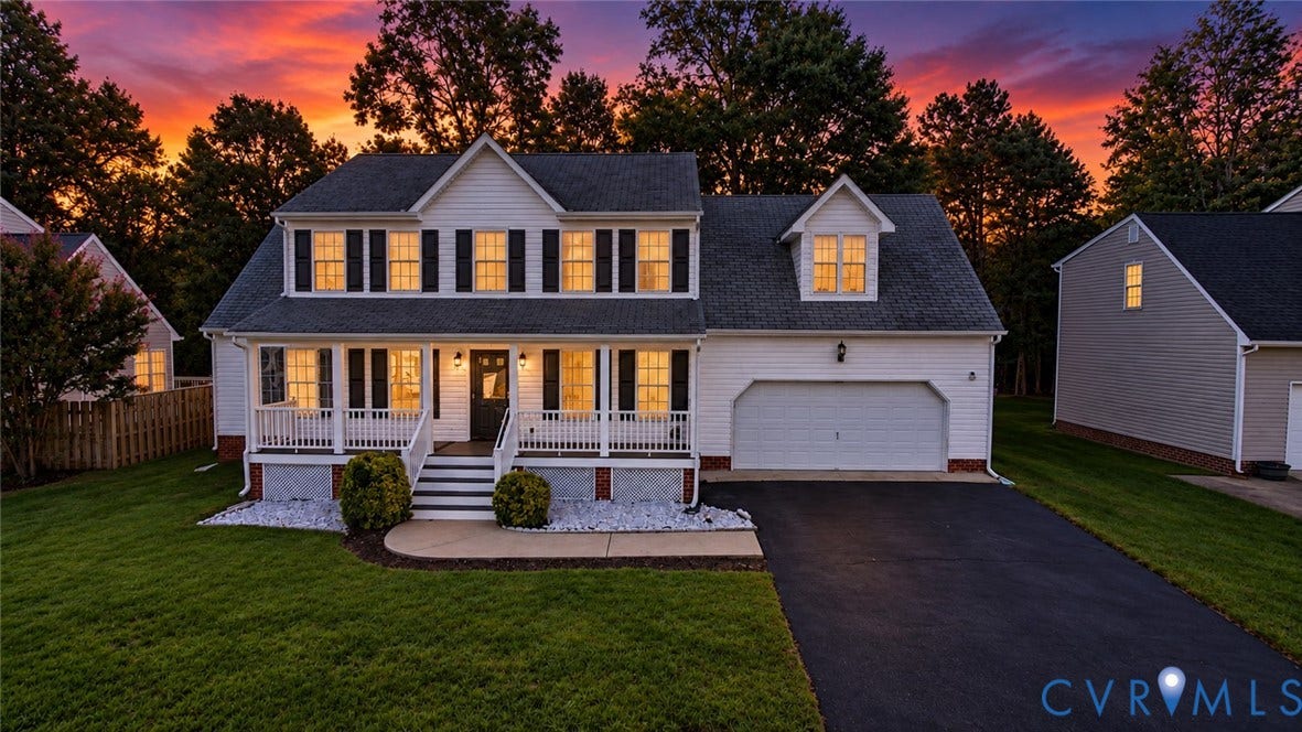 White siding exterior with a dark shingle roof, covered front porch, and an attached two-car garage