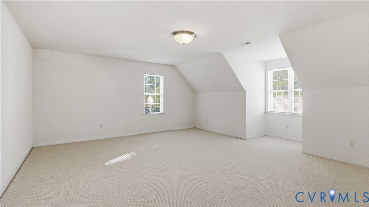 Carpeted flooring, vaulted ceiling, recessed windows, and flush-mount lighting fixture