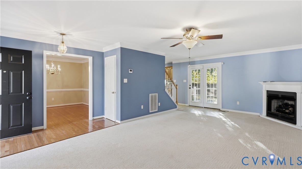 Carpeted living area with a ceiling fan, a white mantel fireplace, and double French doors