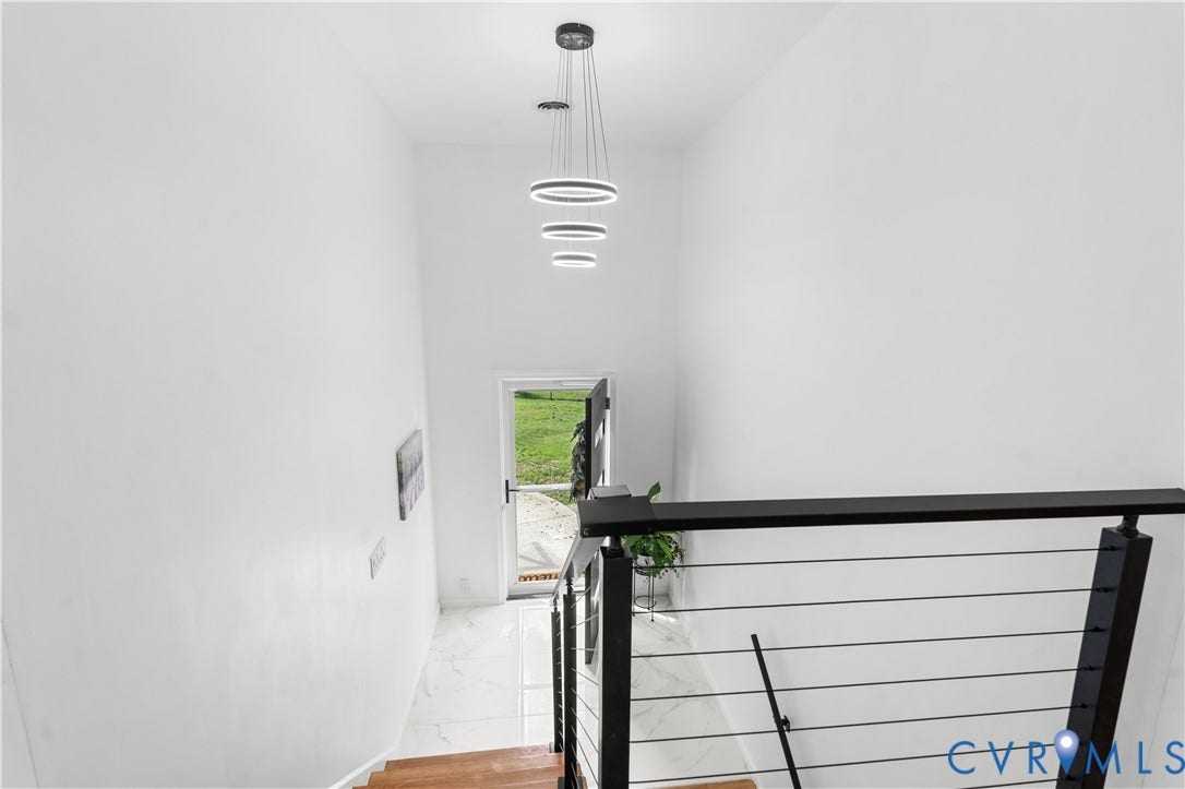 4911 Aqua Lane, Prince George, VA 23875 Hardwood staircase with cable railing, modern ceiling-mounted light fixture, white wall finishes, and tile flooring at landing