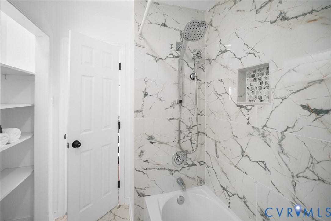 4911 Aqua Lane, Prince George, VA 23875 Bathtub with a chrome fixture, shower system featuring a handheld sprayer, built-in tiled niche, and marble-look wall tiling