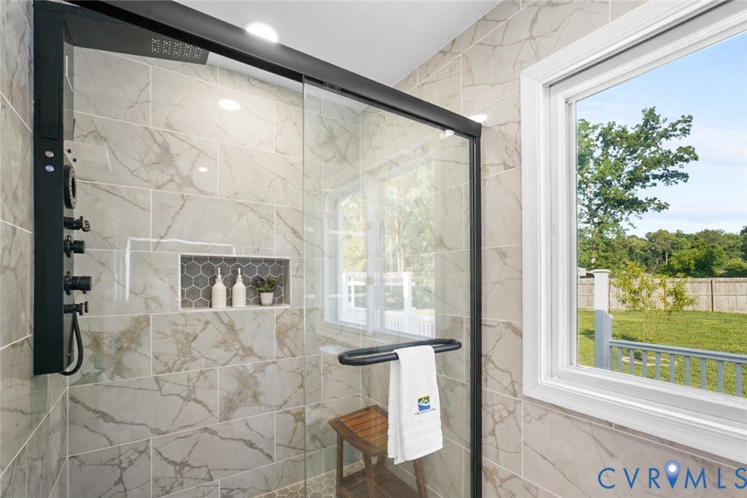 4911 Aqua Lane, Prince George, VA 23875 Walk-in shower with a black-framed glass enclosure, light-toned tiled walls, built-in tiled niche, and a window providing natural light