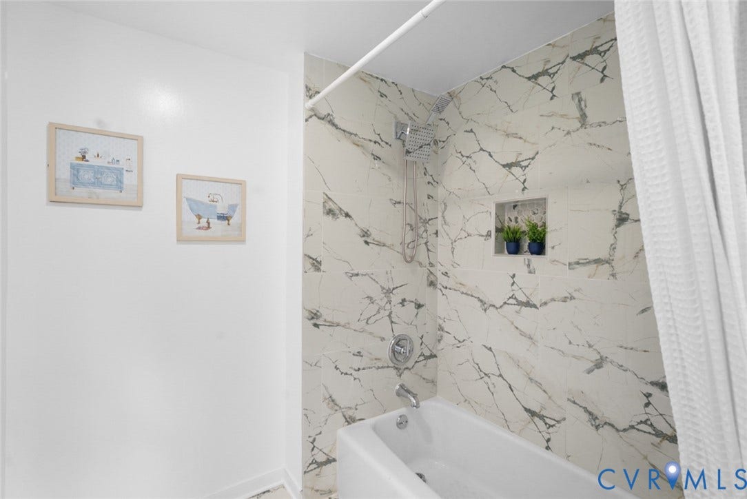 4911 Aqua Lane, Prince George, VA 23875 Bathtub with chrome fixtures, rainfall showerhead, and a tiled shower surround with an integrated niche