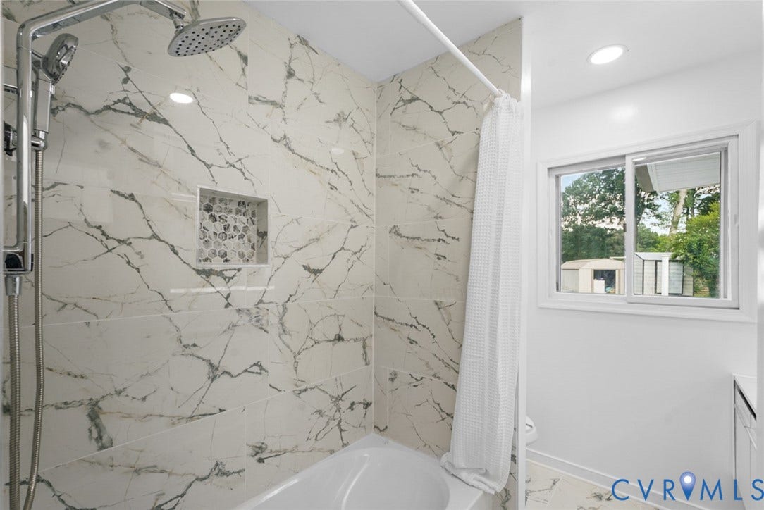4911 Aqua Lane, Prince George, VA 23875 Bathtub with a shower featuring a rain showerhead, a handheld shower, and a tiled niche