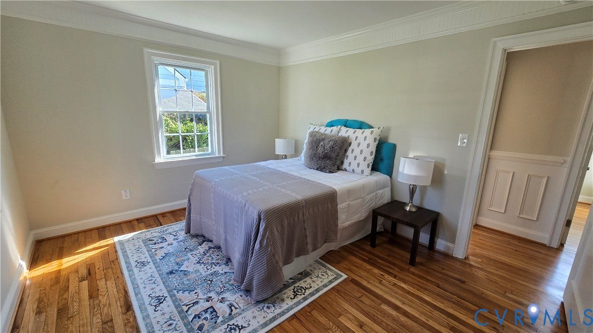 Hardwood flooring, painted walls, crown molding, double-hung window, and a paneled doorway
