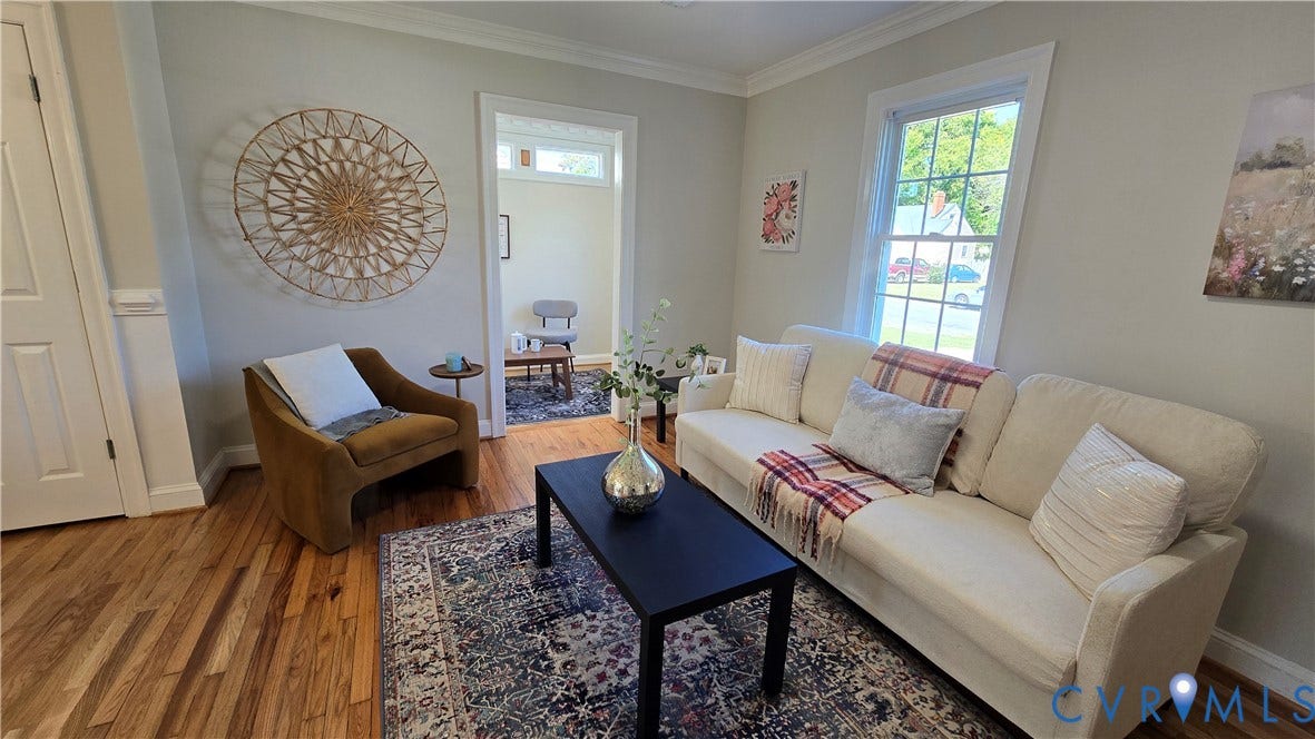 Hardwood flooring throughout, neutral wall tones, crown molding, and a white trim window