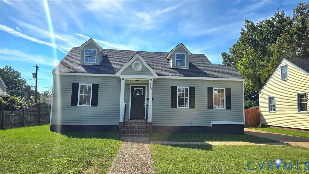 Siding exterior with dormer windows, a dark shingle roof, and a brick-faced entryway