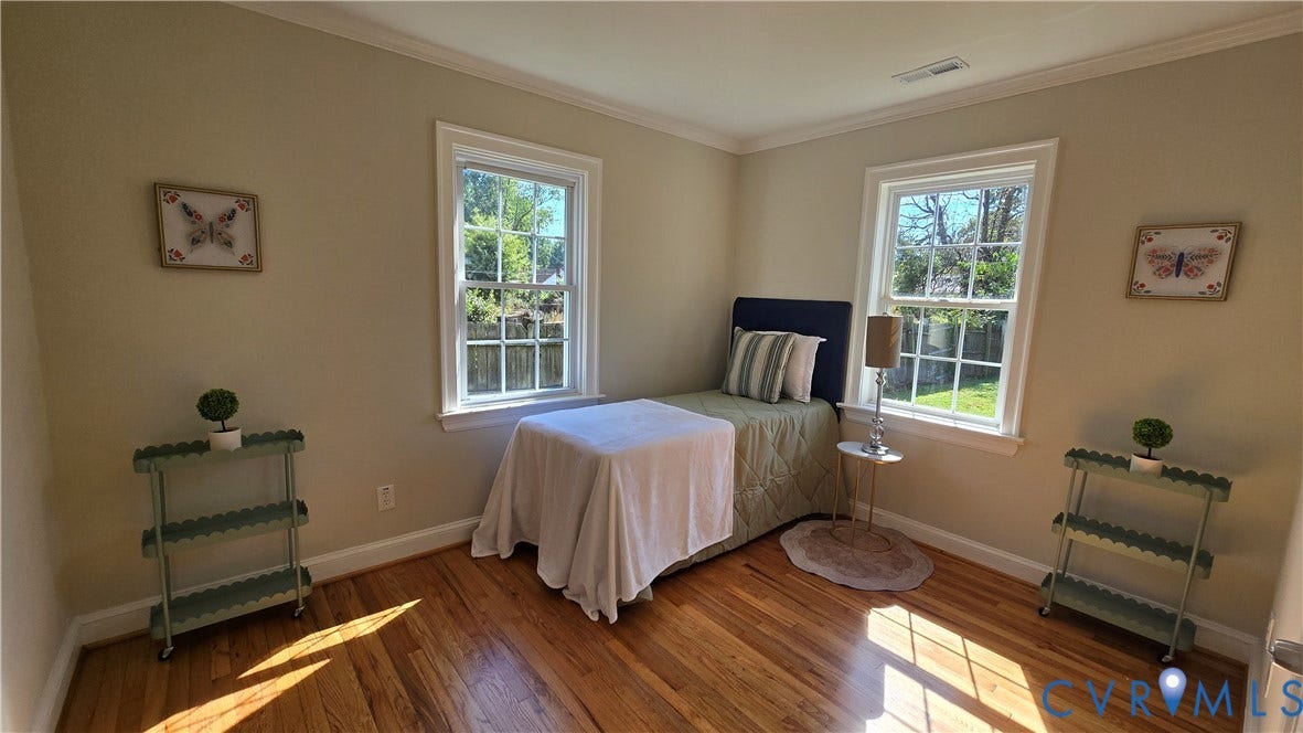Hardwood flooring, painted walls, crown molding, and two windows with white trim