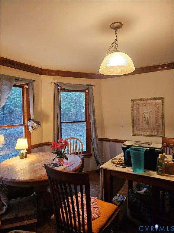 Bay window with natural wood trim, wood-finish flooring, two-tone wall treatment, and a hanging pendant light fixture