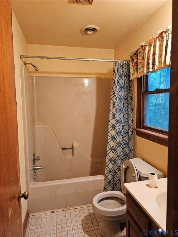 Bathroom featuring a bathtub with an integrated shower, ceramic tile flooring, and a single window