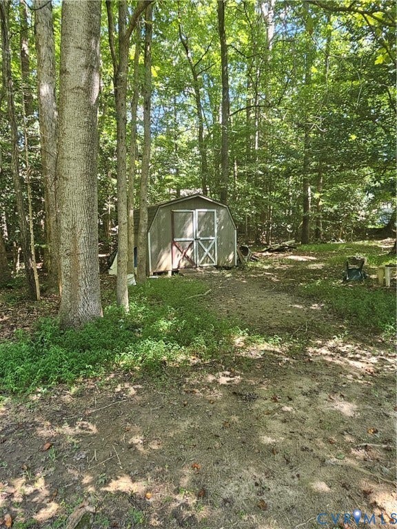 Wooded grounds featuring mature trees and a storage shed
