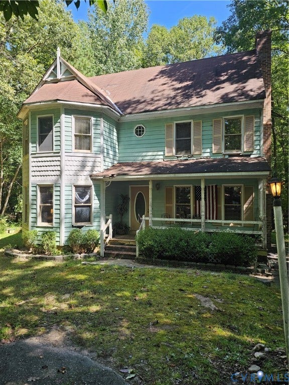 Two-story exterior with teal siding, a covered front porch, an oval-paneled front door, and a brick chimney