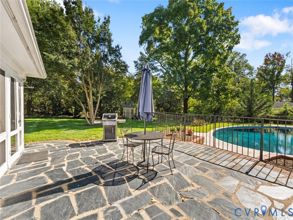 6208 Tapoan Place, Three Chopt, Richmond, VA 23226 Expansive flagstone patio with a curved swimming pool, surrounded by mature trees and a wrought iron fence