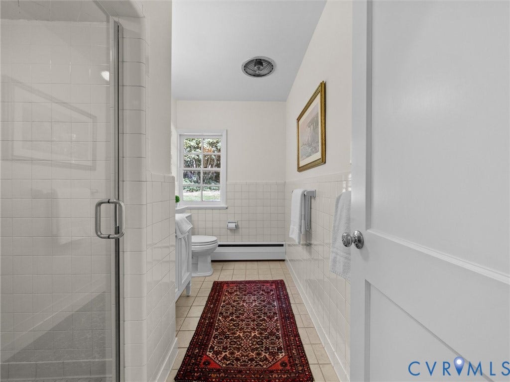 6208 Tapoan Place, Three Chopt, Richmond, VA 23226 Shower enclosure with clear glass door, white tiled walls, window with exterior foliage, white toilet, and tile flooring