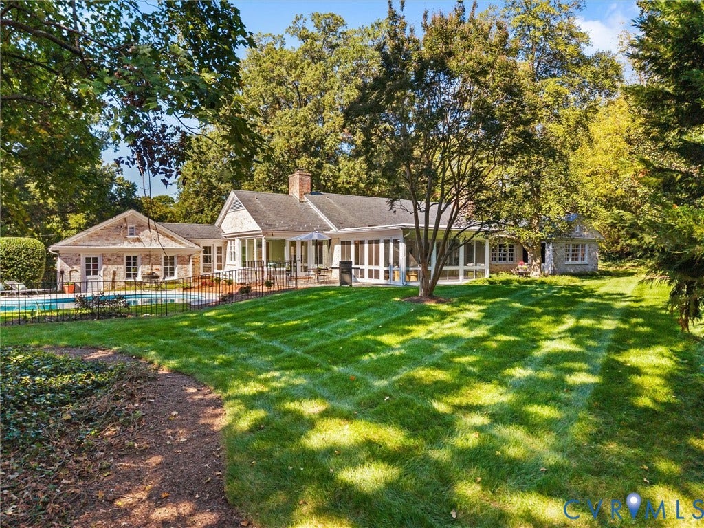 6208 Tapoan Place, Three Chopt, Richmond, VA 23226 Expansive backyard featuring a manicured lawn, mature trees, a swimming pool with a black wrought iron fence, a stone-clad exterior, and a detached structure