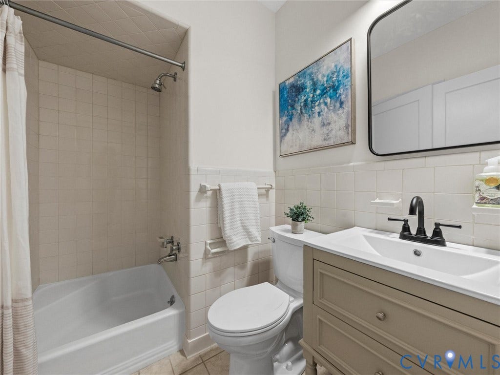 6208 Tapoan Place, Three Chopt, Richmond, VA 23226 Bathroom featuring a bathtub with overhead shower, ceramic wall tiling, a vanity with a rectangular sink, a matte black faucet, and a wall-mounted mirror