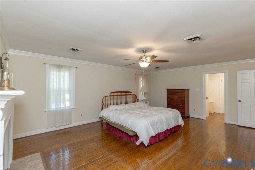 Wood-finish flooring, crown molding, ceiling fan with light fixture, and a white interior door