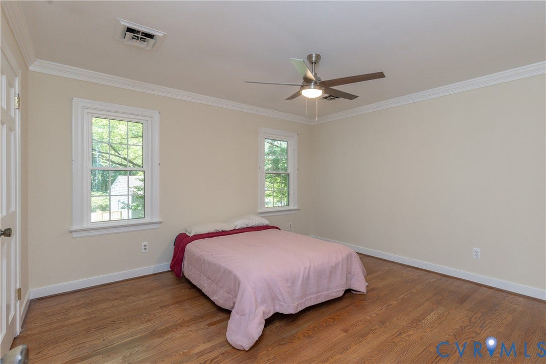 Hardwood flooring, crown molding, double windows, ceiling fan with integrated lighting, and a paneled door