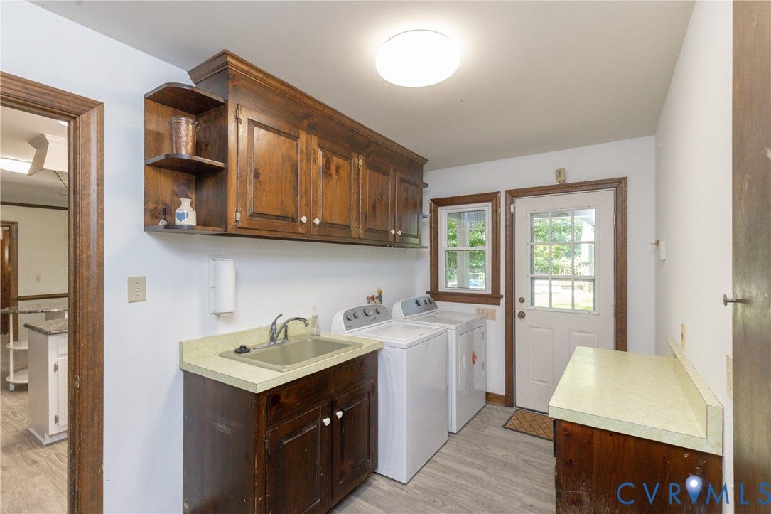 Laundry area with wood-finish cabinetry, a utility sink, and wood-finish flooring