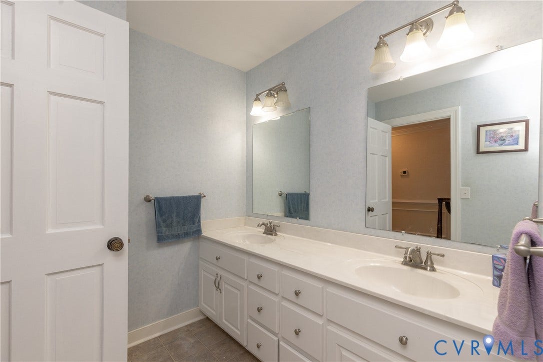 Double vanity with integrated sinks, white cabinetry, and brushed nickel hardware