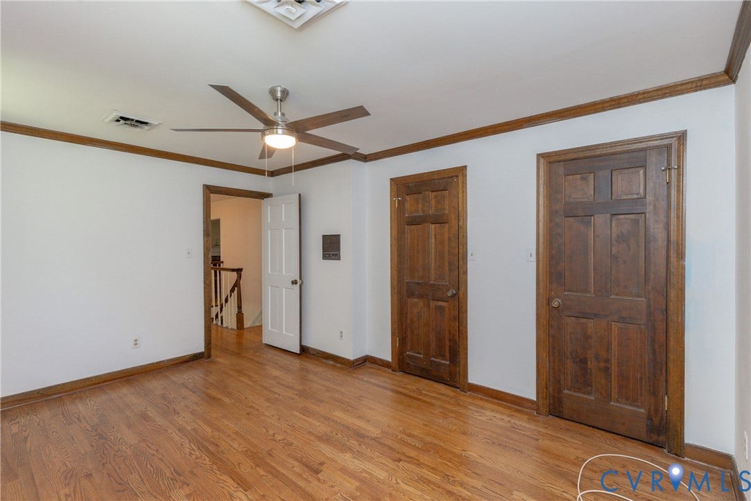 Hardwood flooring, wood trim and door frames, two panel doors, and a ceiling fan with integrated lighting