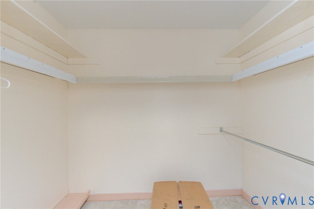 Recessed closet featuring light neutral wall tones, built-in shelving, and a garment rod